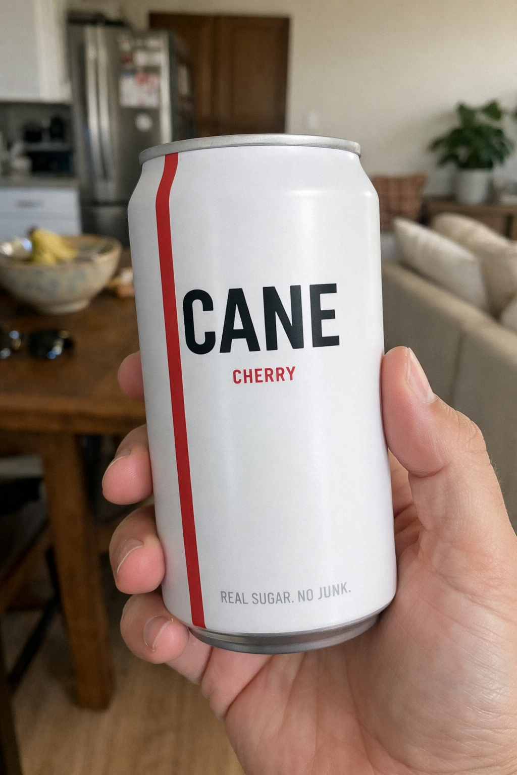 Someone holding a CANE Cherry soda can — real sugar, no junk.